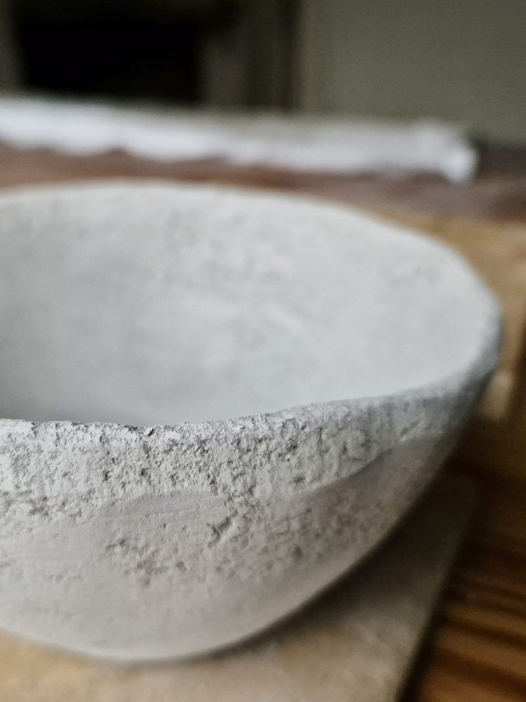 Schlichte, graue Schale aus Ton auf einem Holzuntergrund.