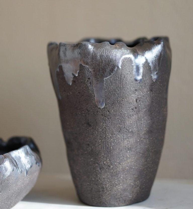 Große, dunkle Vase aus Steinzeugkeramik auf einer Marmorplatte.