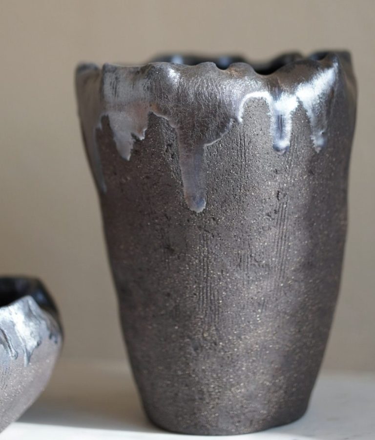 Eine moderne Tischlampe neben einem Kerzenständer mit weißen Kerzen auf Holz