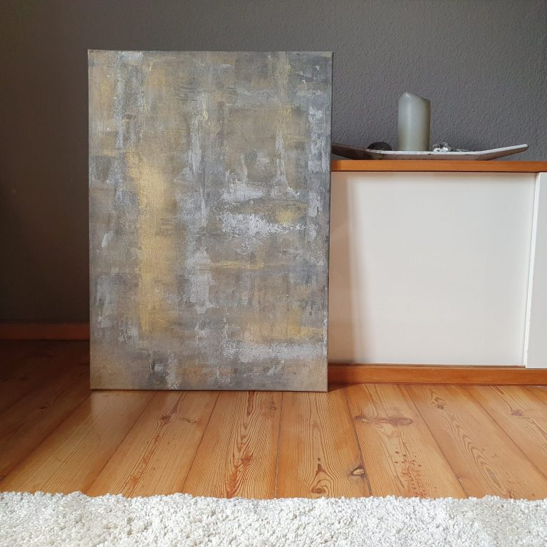 Graues, abstraktes Gemälde vor einer hellen Wand auf einem Holzboden.