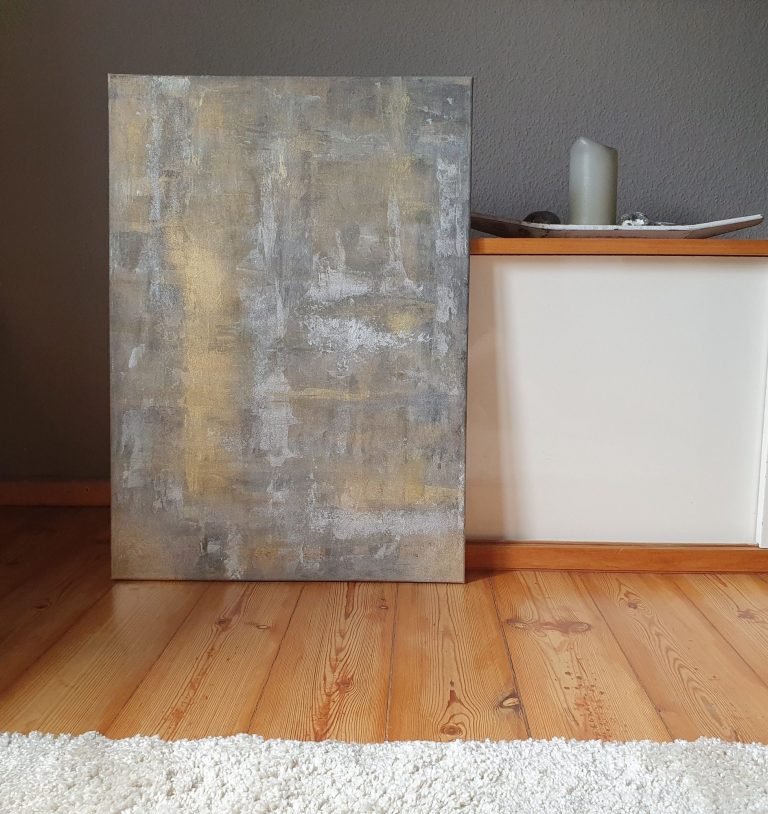 Ein abstraktes Kunstwerk steht vor einem Sideboard  auf dem Boden und auf einem weißen Teppich.