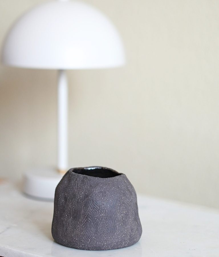 Eine moderne Tischlampe neben einem Kerzenständer mit weißen Kerzen auf Holz