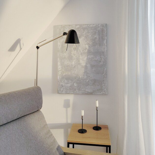 Eckbereich mit einer Lampe, einem Bild, einem Beistelltisch und zwei Kerzenhaltern.
