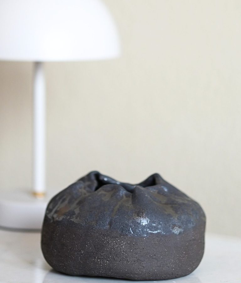 Eine moderne Tischlampe neben einem Kerzenständer mit weißen Kerzen auf Holz