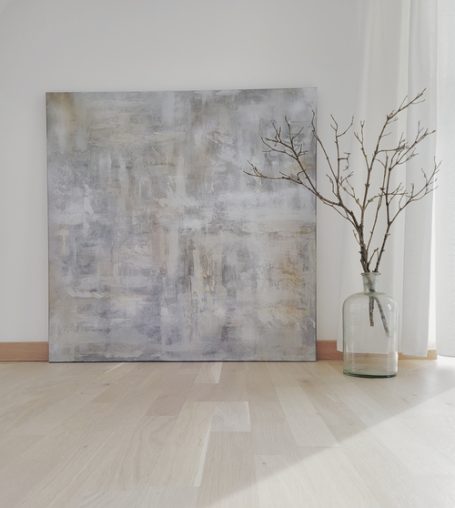 Abstraktes Kunstwerk in Grautönen neben einem minimalistischen Zweig in einer Vase.