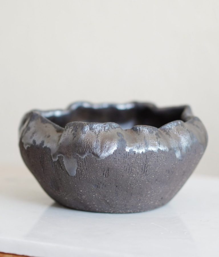 Eine moderne Tischlampe neben einem Kerzenständer mit weißen Kerzen auf Holz