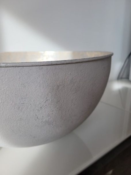 Graue Schüssel auf einer weißen Oberfläche.