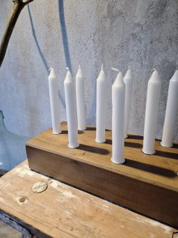 Ein Holzkerzenhalter mit weißen Kerzen.