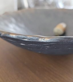 Schale aus dunklem Steinzeugton mit einer unregelmäßigen Kante und natürlicher Dekoration.