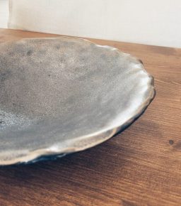 Schüssel aus Steinzeugton mit organischem Rand auf einem Holztisch.