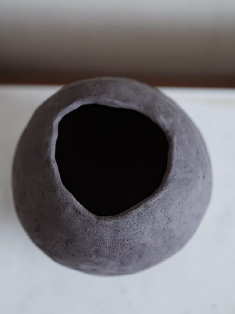 Schlichte, große Vase aus Keramik auf einer Marmorplatte.