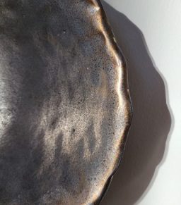 Schwarzes, glänzendes Dekoschale mit wellenförmigem Rand.